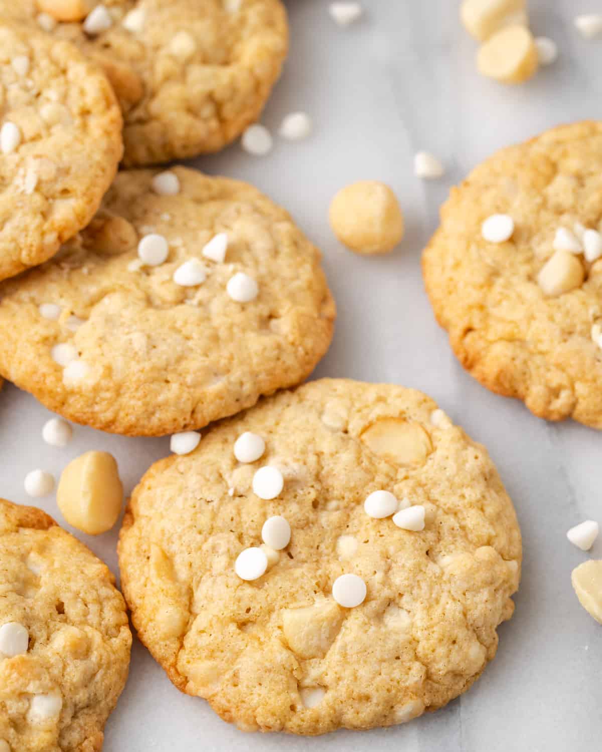 Gluten free white chocolate macadamia nut cookies scattered on a white table. 