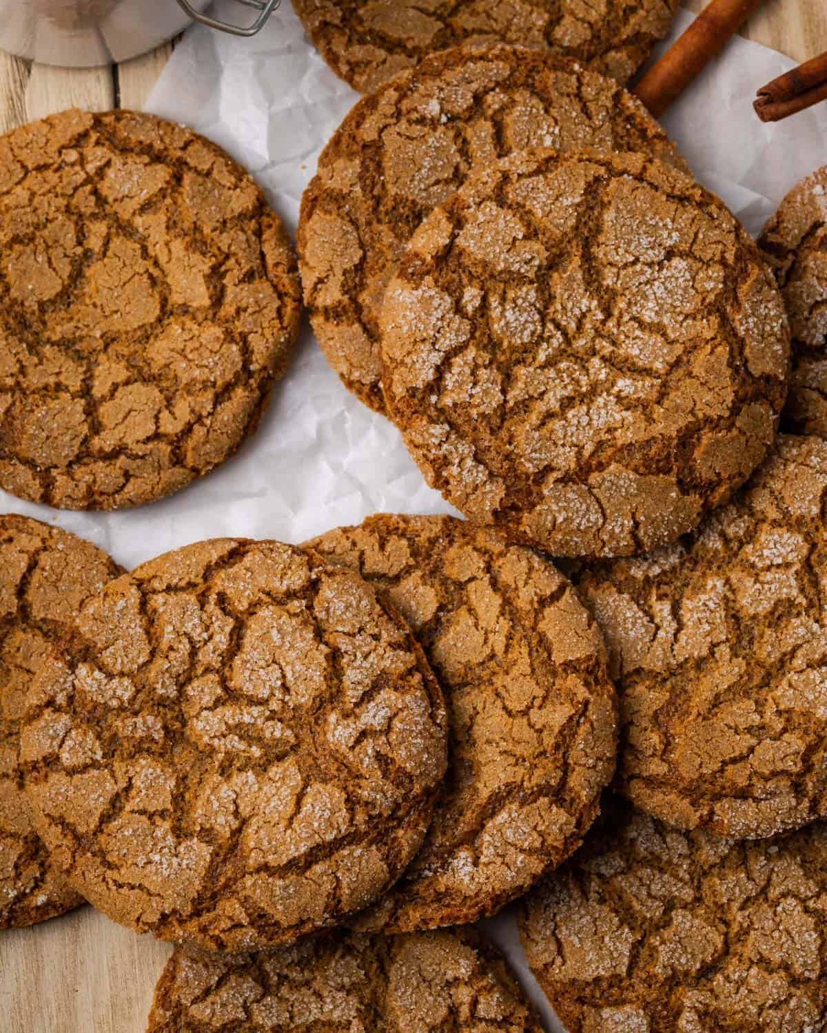 A batch of gluten free molasses cookies spread out on a wood tabletop.
