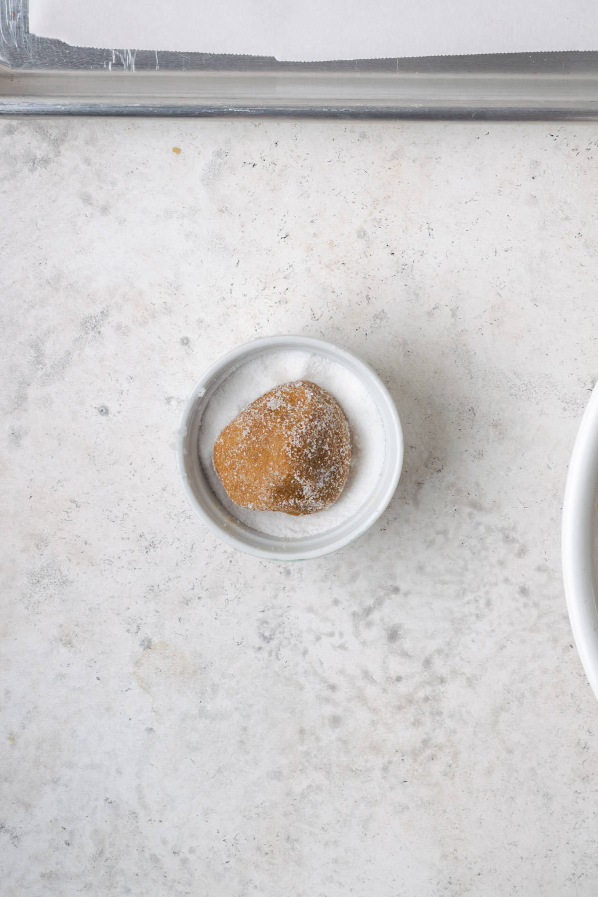 A ball of molasses cookie dough rolled in white sugar.