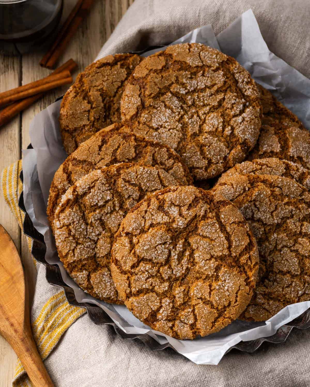 A stack of gluten free molasses cookies sitting on a metal baking dish.