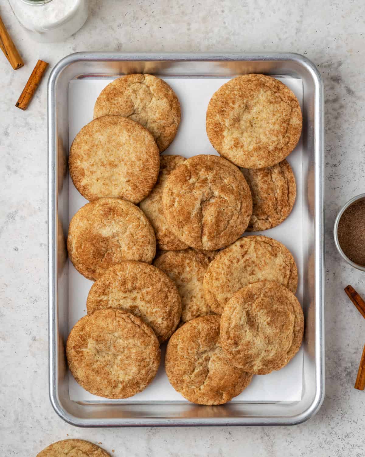 A baking tray piled with gluten free snickerdoodles sitting on a white table.