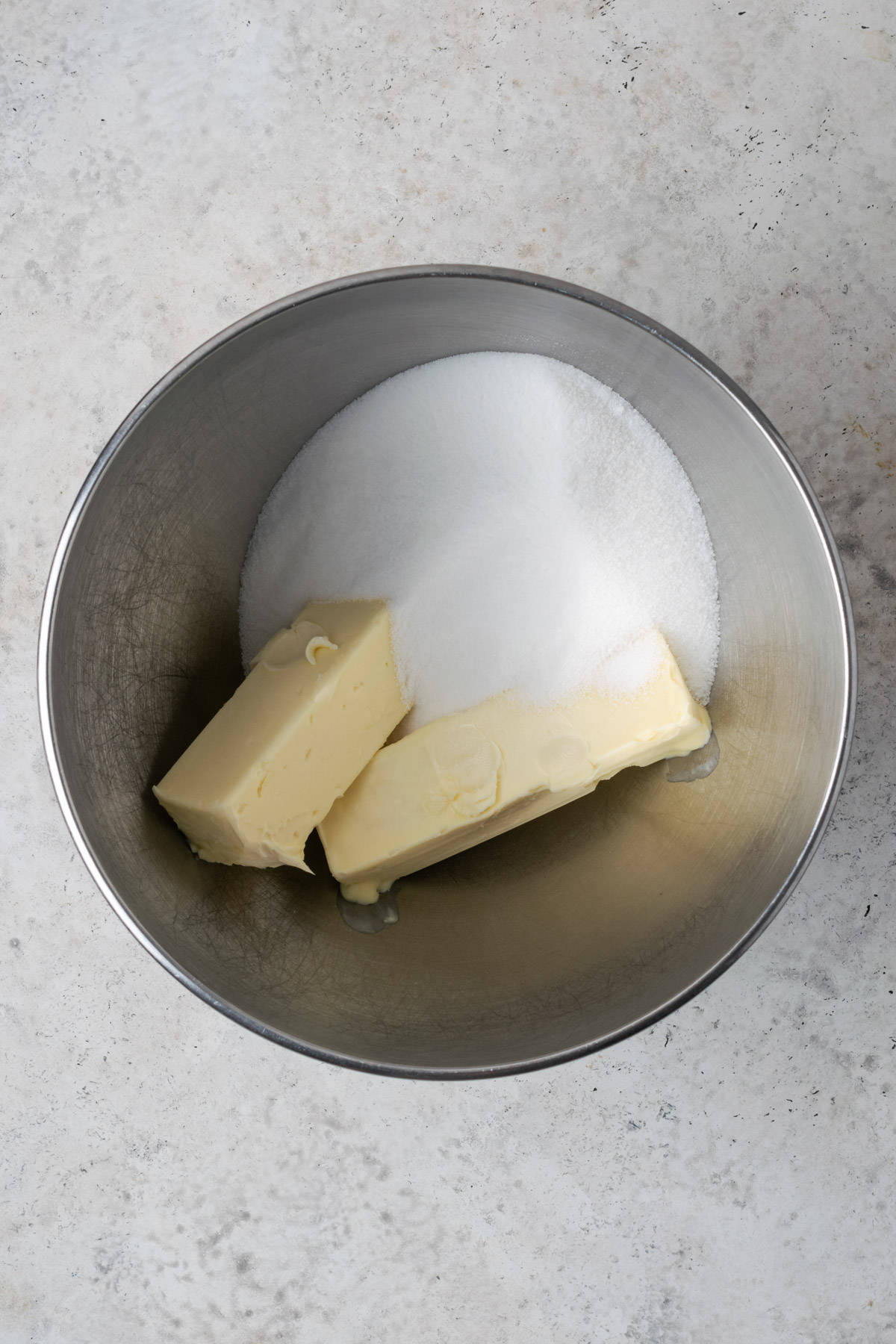 Butter and sugar combined in a large metal mixing bowl. 