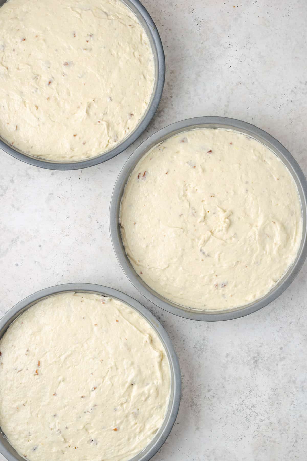 Three cake rounds filled with unbaked Italian cream cake batter.