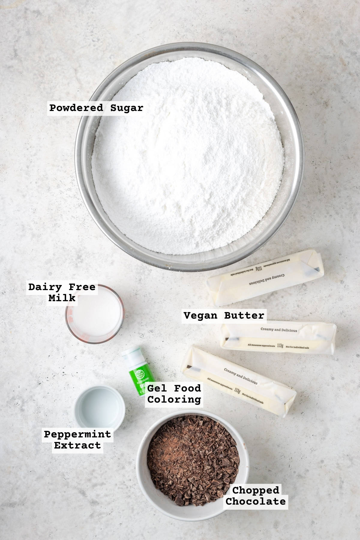 Ingredients for mint chocolate chip frosting on a white table.