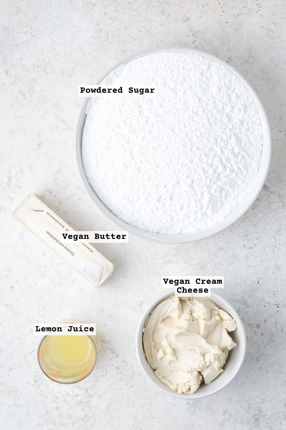 Ingredients for dairy free lemon cream cheese frosting on a white table.