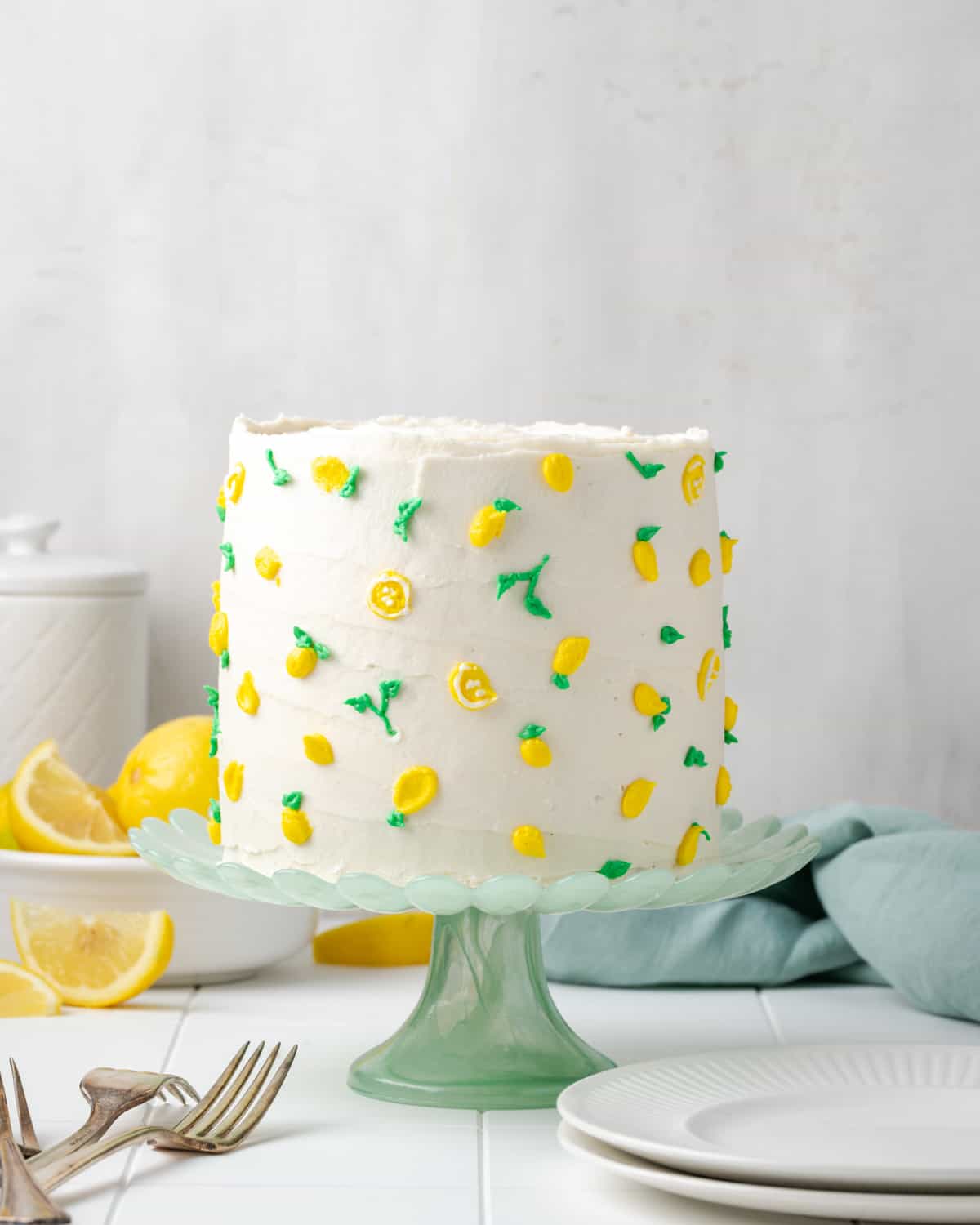 A gluten free lemon cake sitting on a green glass cake stand.