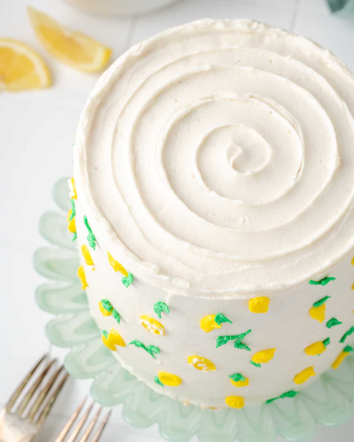 A fully decorated gluten free lemon cake sitting on a green cake stand. 