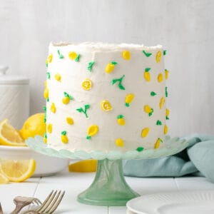 A decorated gluten free lemon cake sitting on a green cake stand.