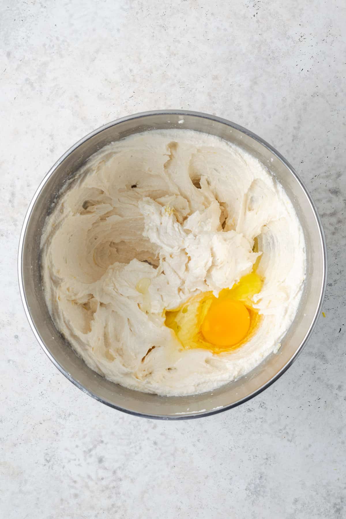 An egg added to the partially mixed lemon cake batter.