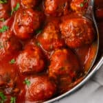 Gluten free meatballs in marinara sauce being served from a pan.