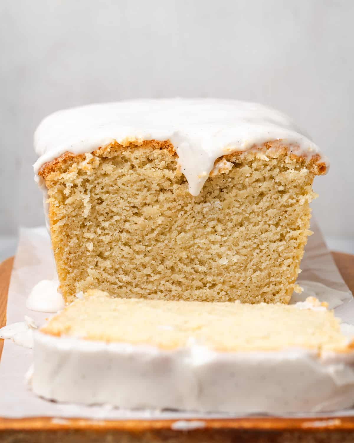 A loaf of pound cake sliced with icing dripping over the edge.