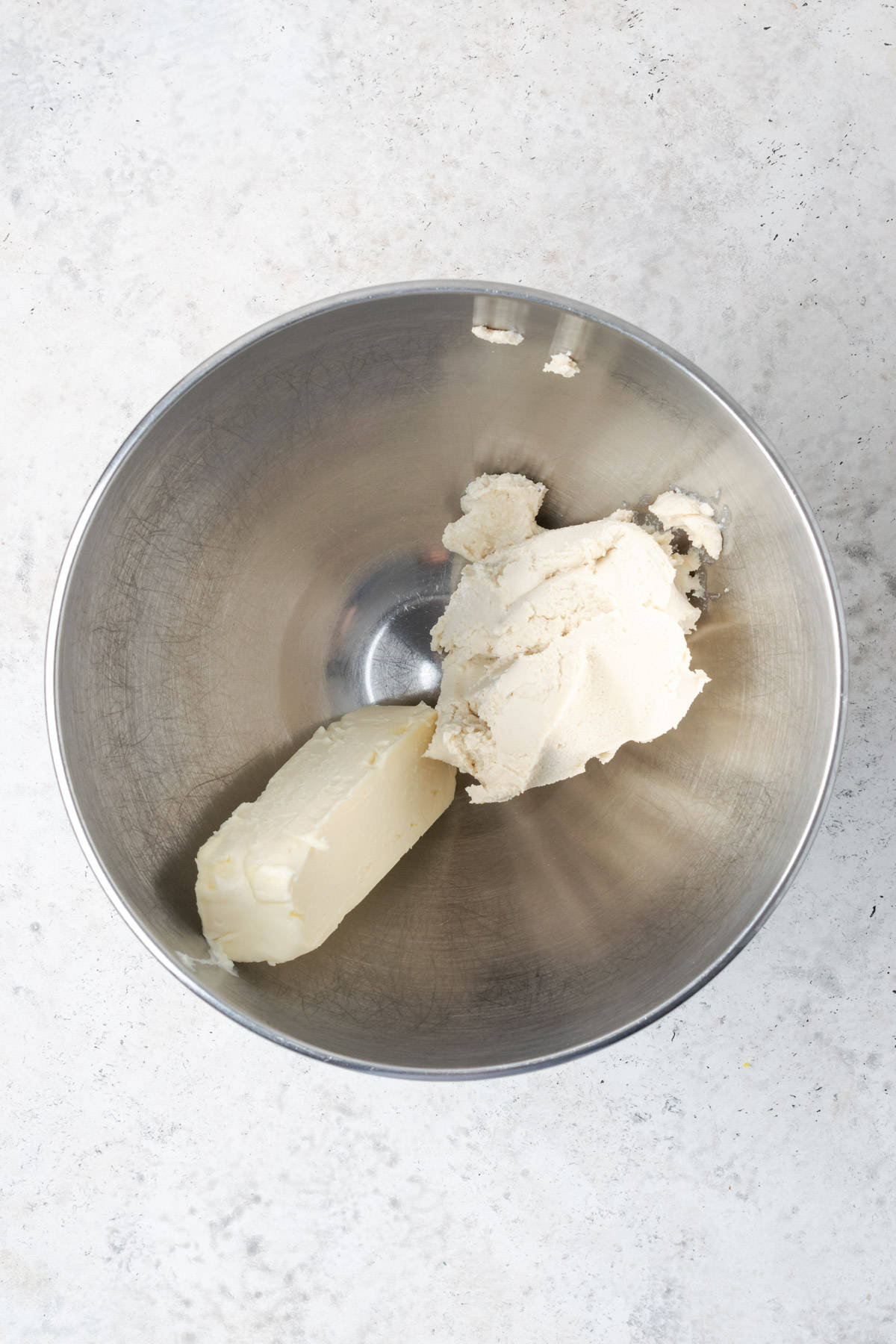 Vegan butter and vegan cream cheese in a large metal mixing bowl.