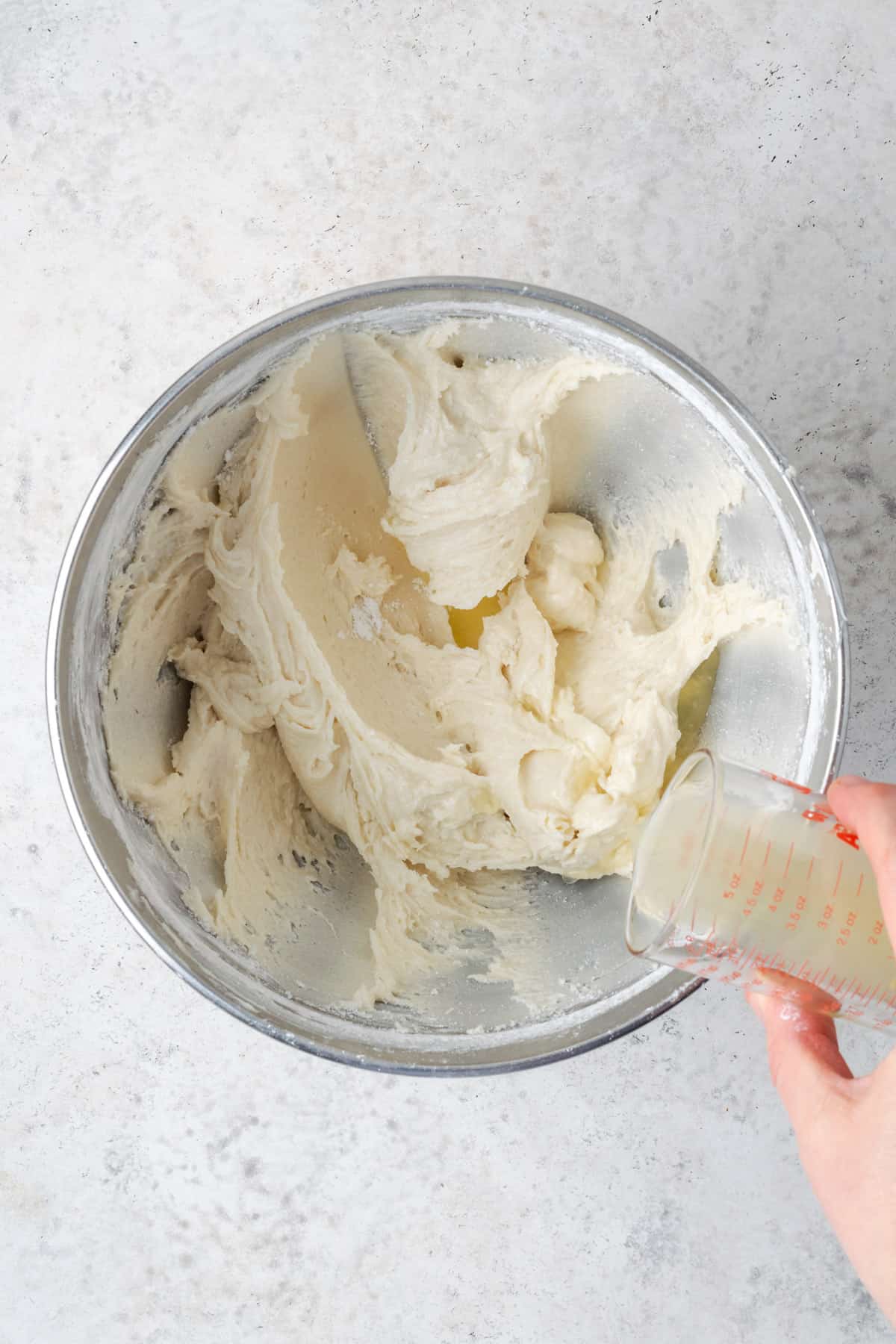 Lemon juice being poured into the cream cheese frosting.