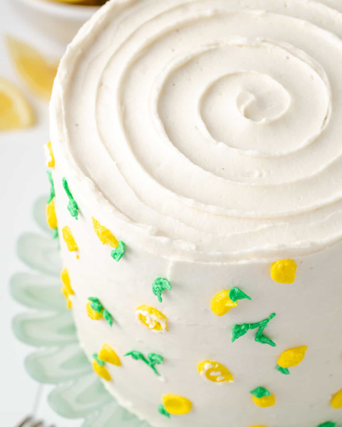 A layer cake topped with lemon cream cheese frosting and decorated with buttercream lemons.