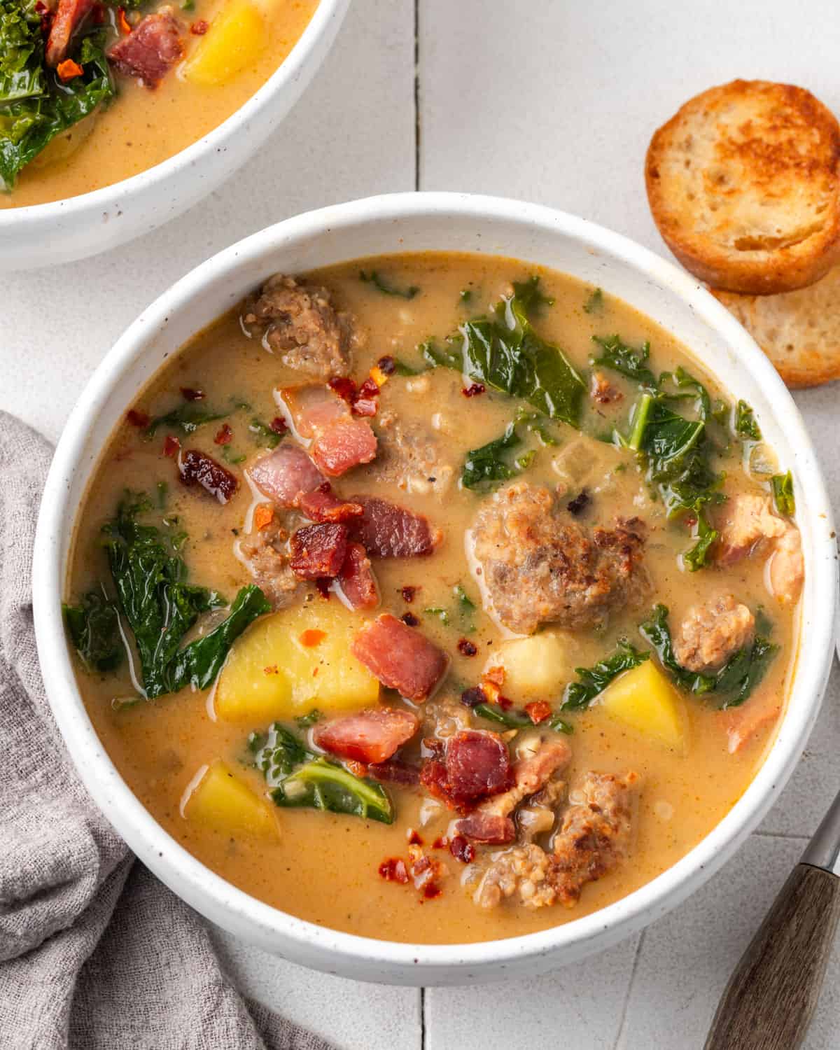 A bowl of zuppa toscana soup served with garlic bread. 