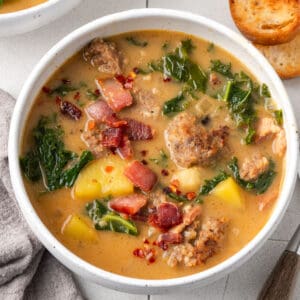 A bowl of zuppa toscana soup topped with bacon pieces.