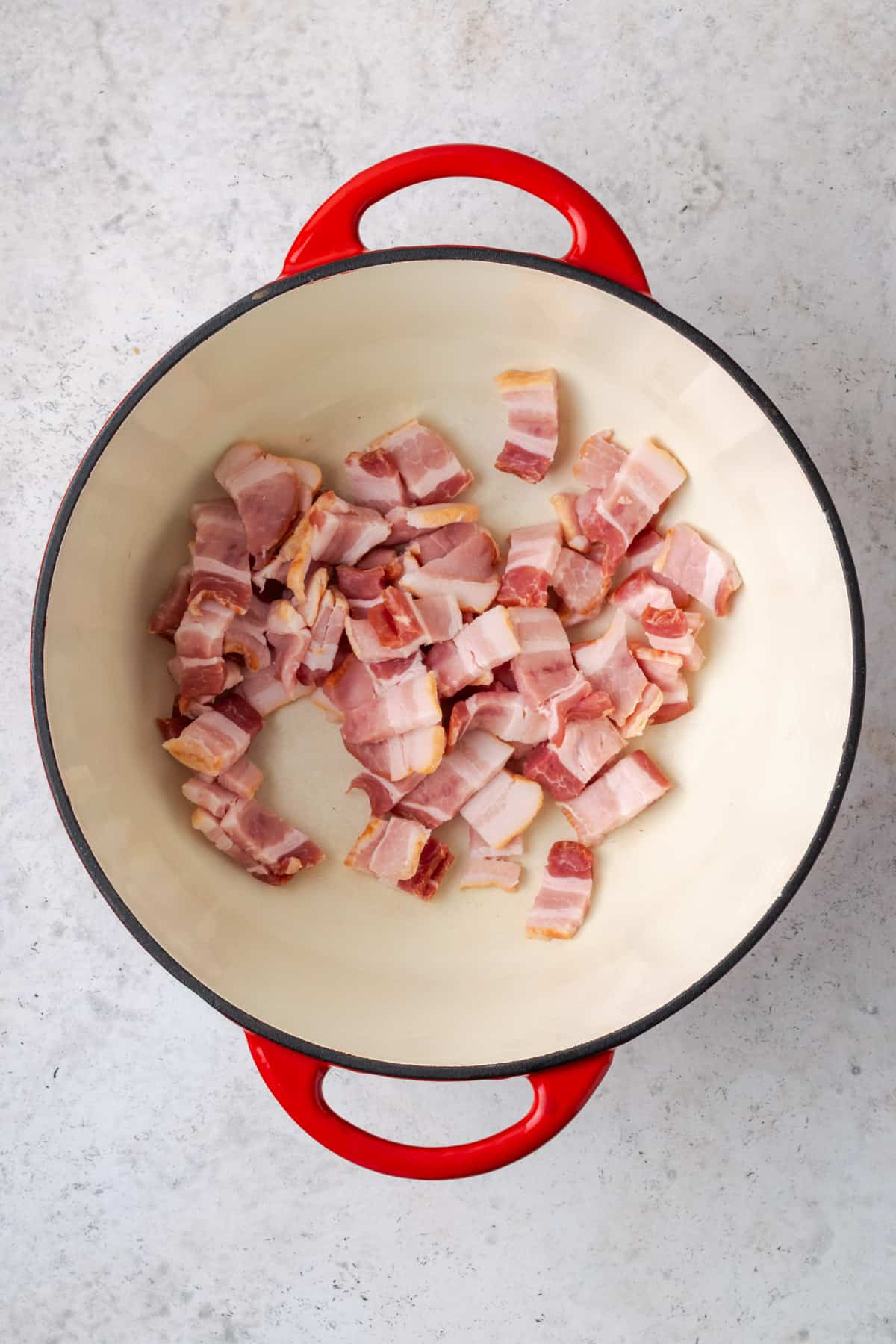 Pieces of bacon being cooked in a large soup pot.