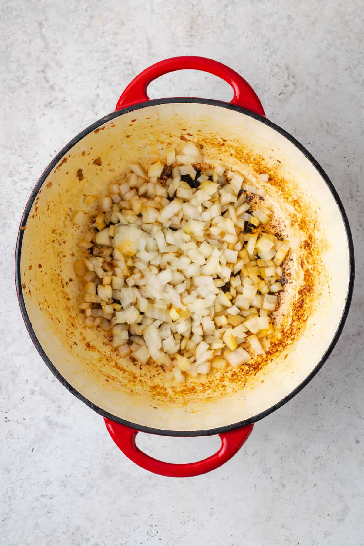 Diced onion being sauteed in a dutch oven pot.