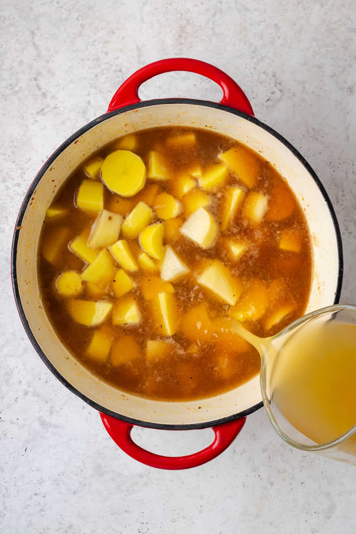 Potatoes and chicken broth added to the cooked onions in the soup pot.