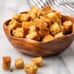 A bowl of gluten free croutons sitting on a white table.
