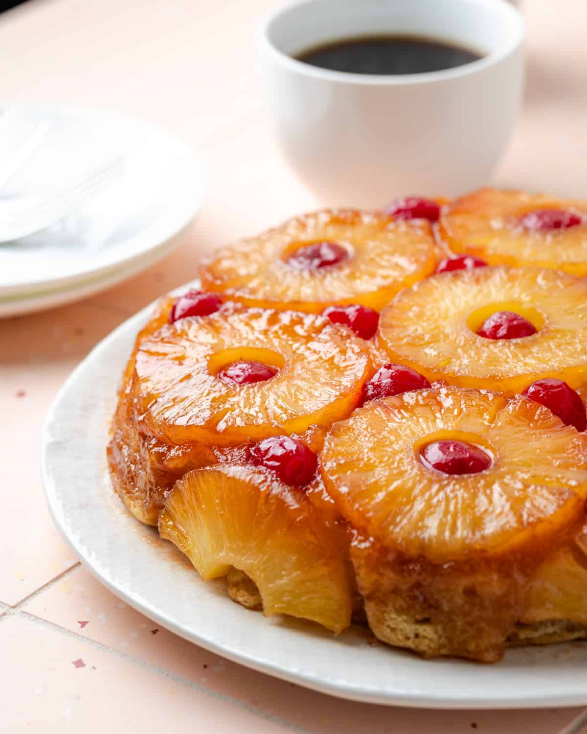 A vegan pineapple upside down cake sitting on a pink table. 