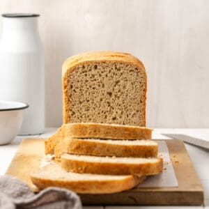 A sliced loaf of gluten free sandwich bread sitting on a cutting board.