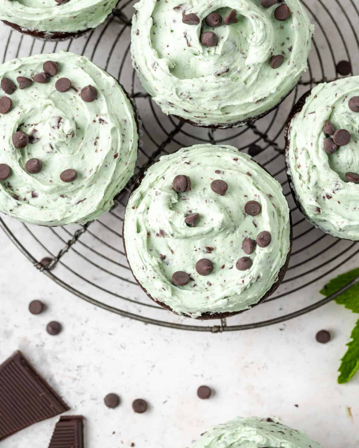 A batch of mint chocolate cupcakes sitting on a metal cooling rack. 