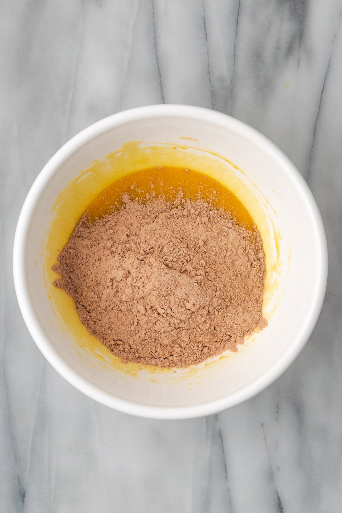 Dry ingredients being added to the wet ingredients in the mixing bowl. 