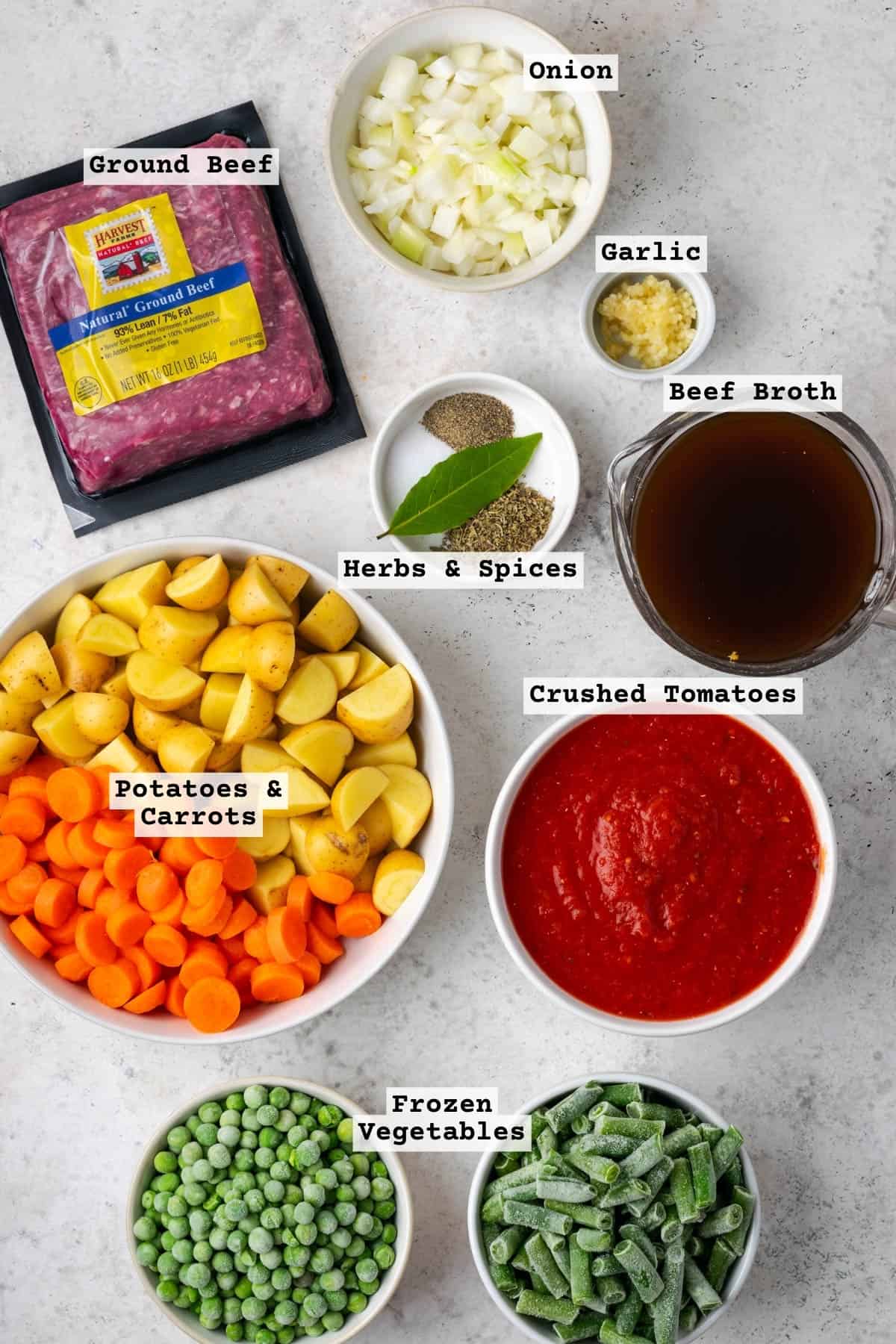 Ingredients for hamburger soup sitting on a white table.