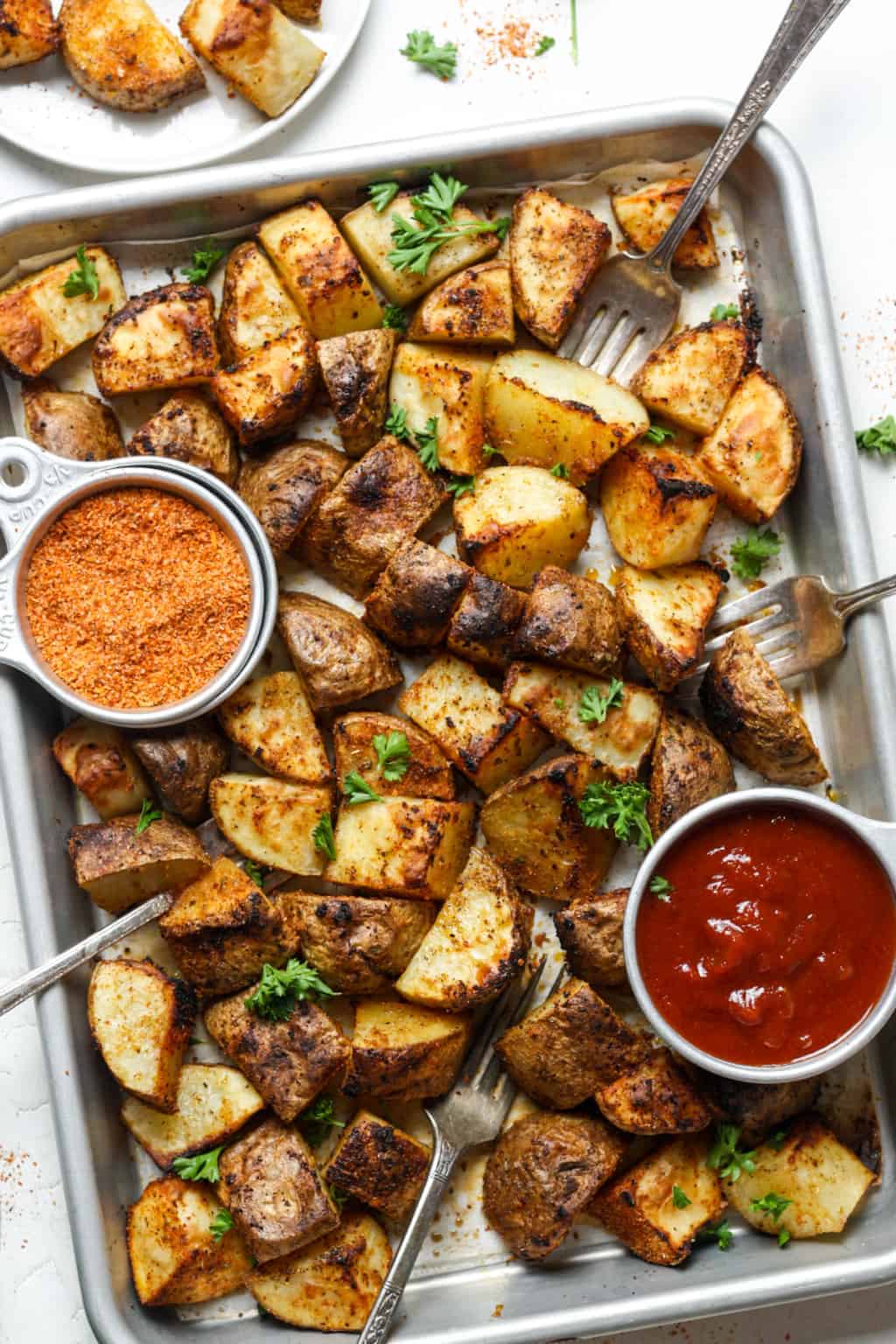 Roasted Mexican potatoes with dipping sauce on a small metal tray.