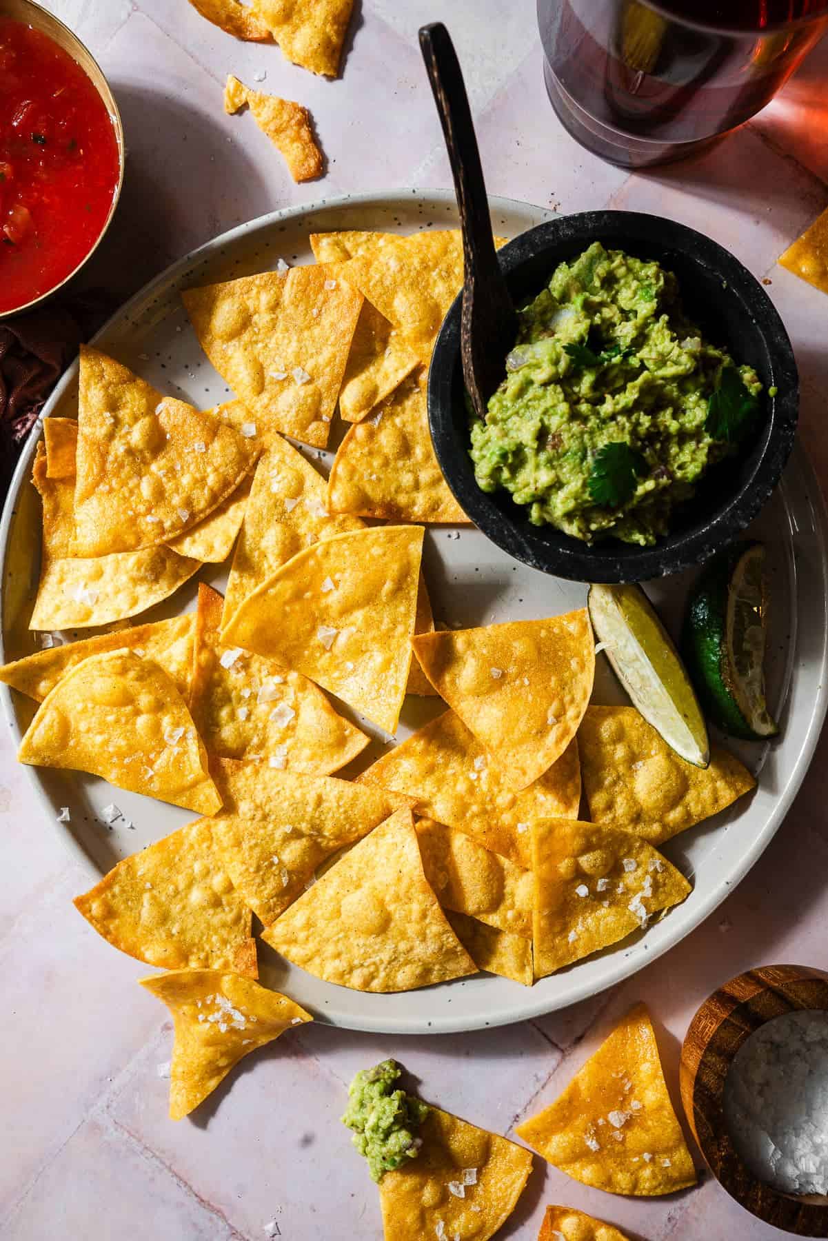 A plate of homemade corn tortilla chips served with salsa and guacamole.