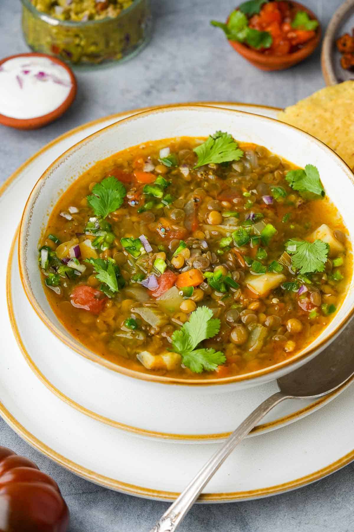 A bowl of Mexican lentil soup topped with pieces of fresh cilantro.