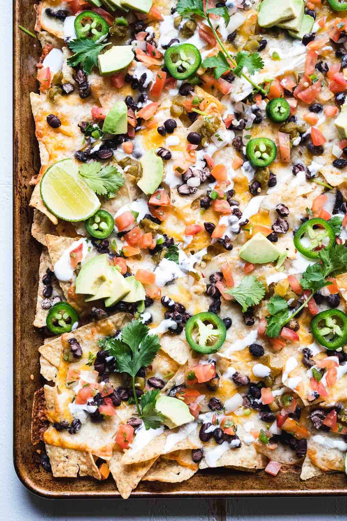 Baked nachos sitting on a large metal baking sheet.