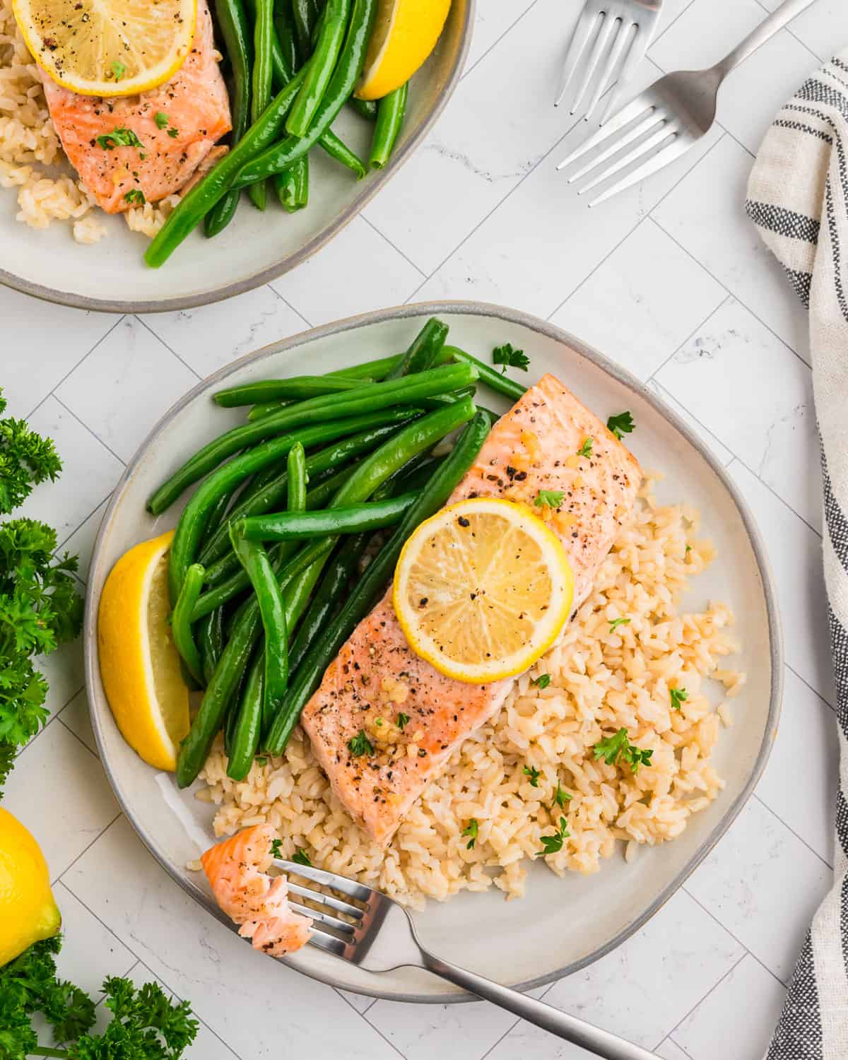 Lemon pepper salmon served on a white plate with rice and green beans.