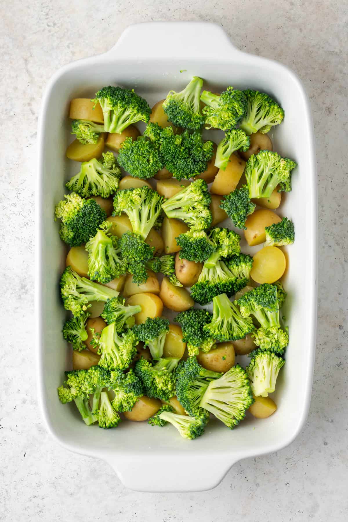 Broccoli added on top of the potatoes in the casserole dish.