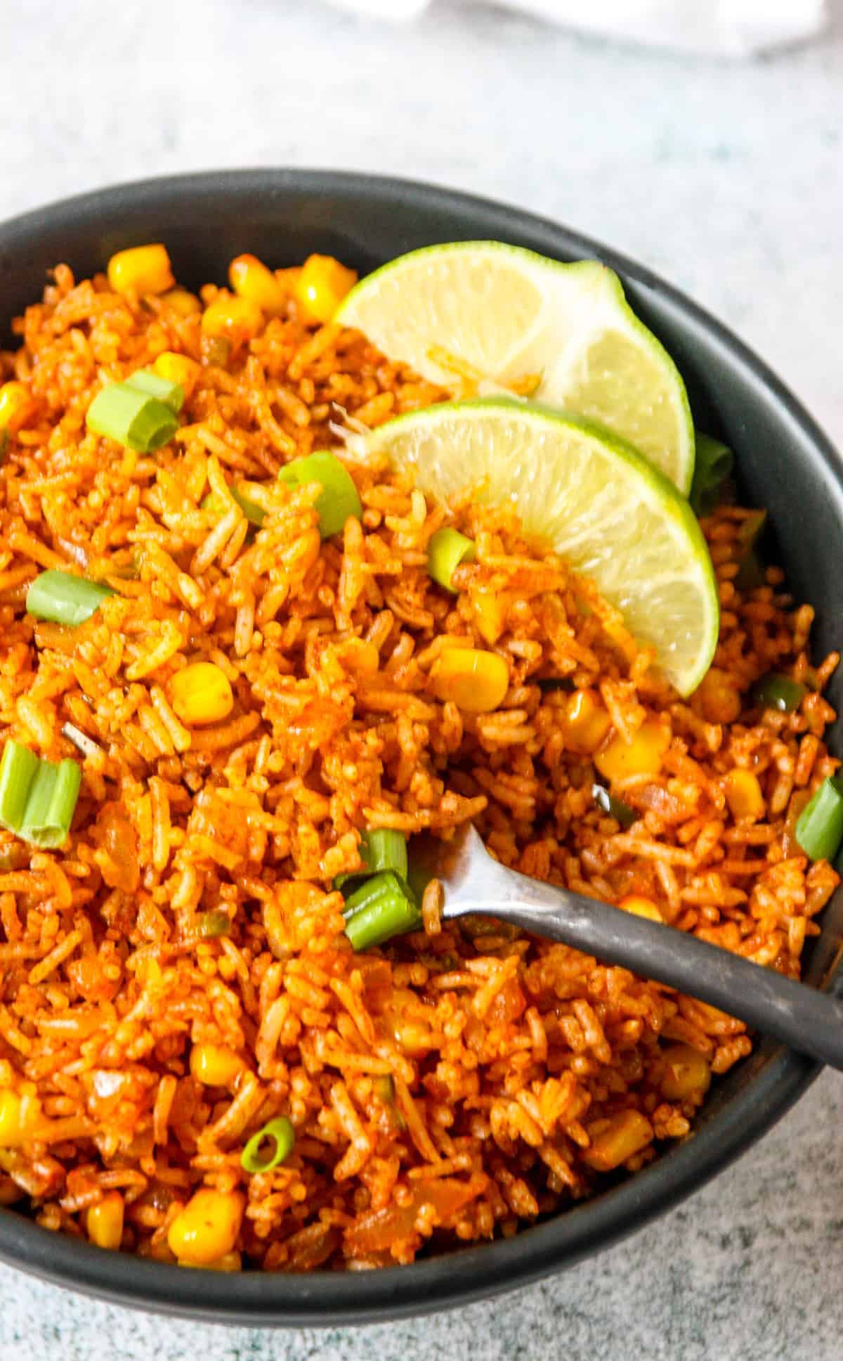 A bowl of Mexican red rice sitting on a countertop.