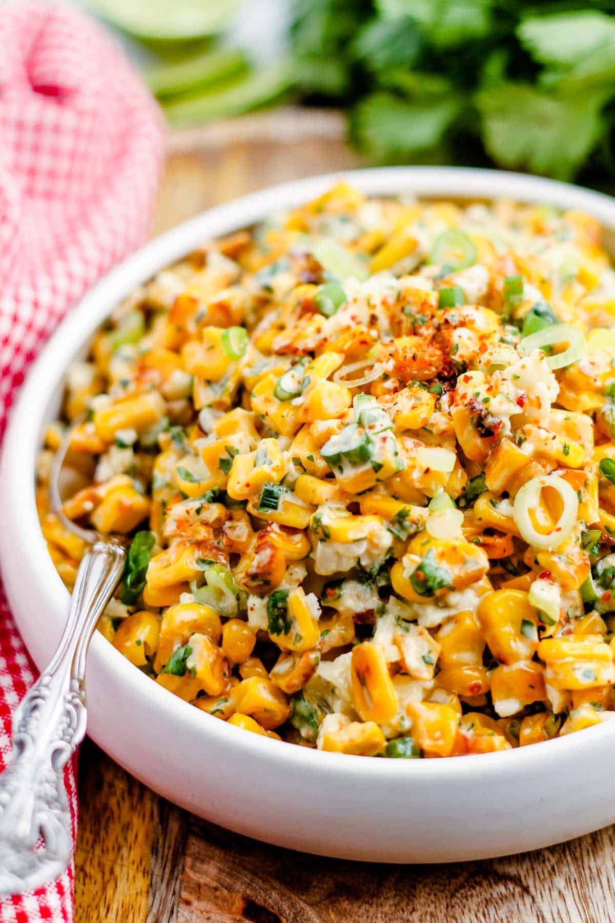 A bowl of Mexican street corn sitting on a wood table.