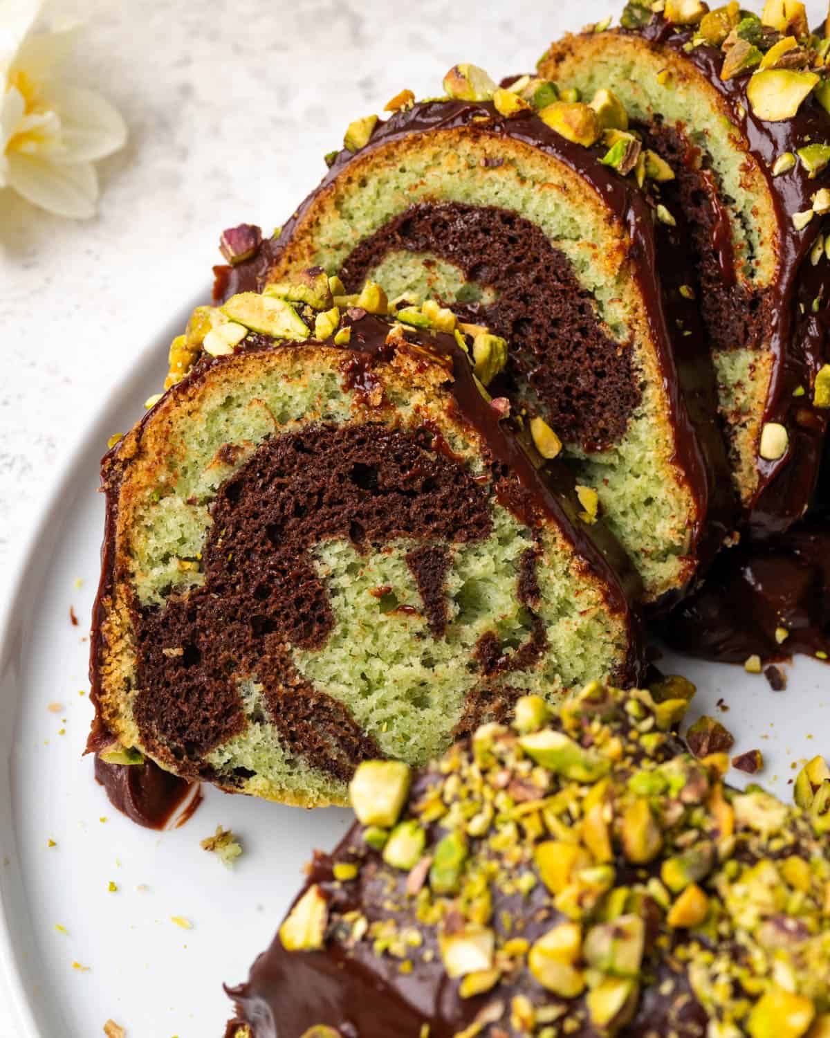 A sliced pistachio chocolate bundt cake showing the interior of light green cake with chocolate swirls.