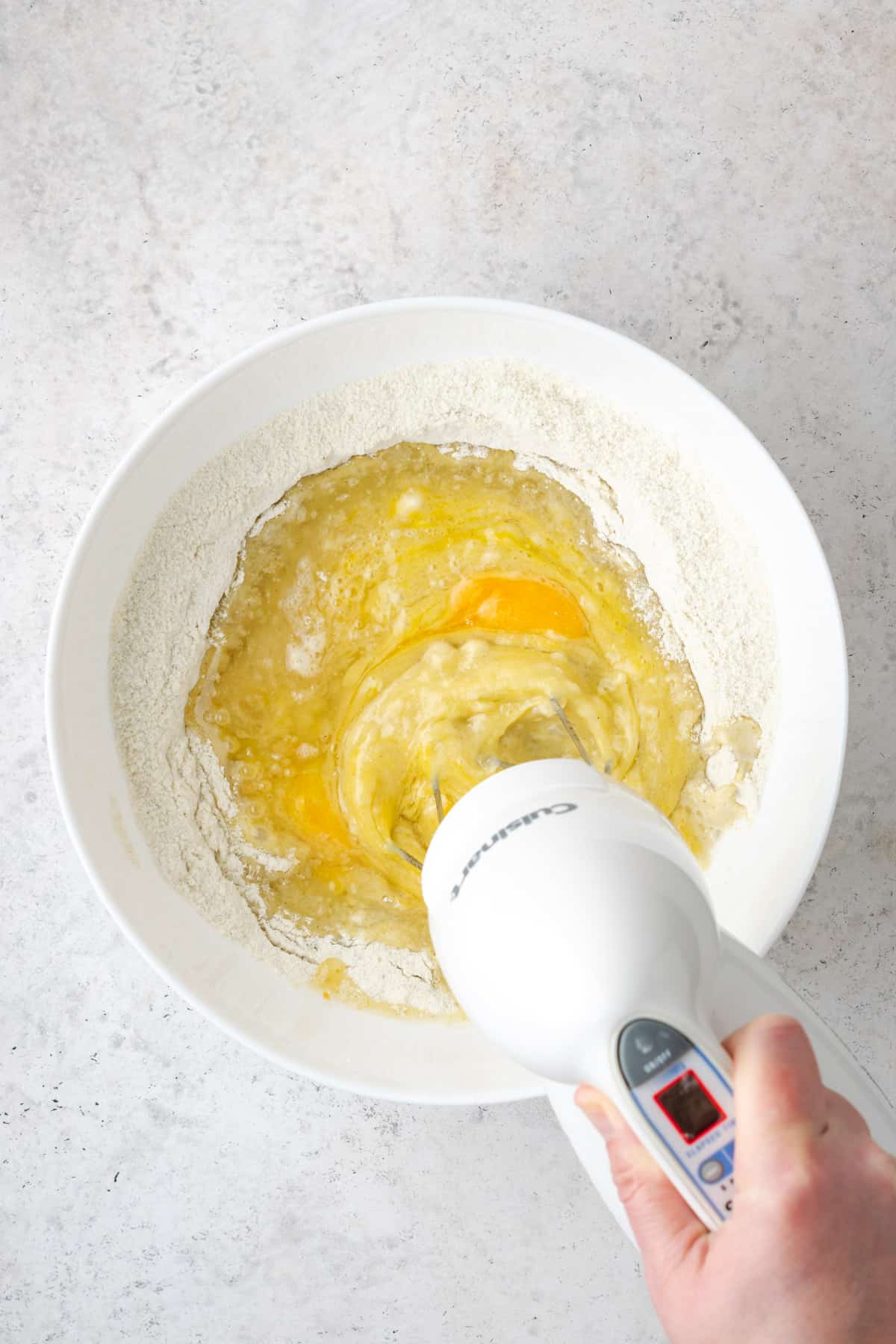 Pistachio cake batter being mixed together with a handheld mixer.