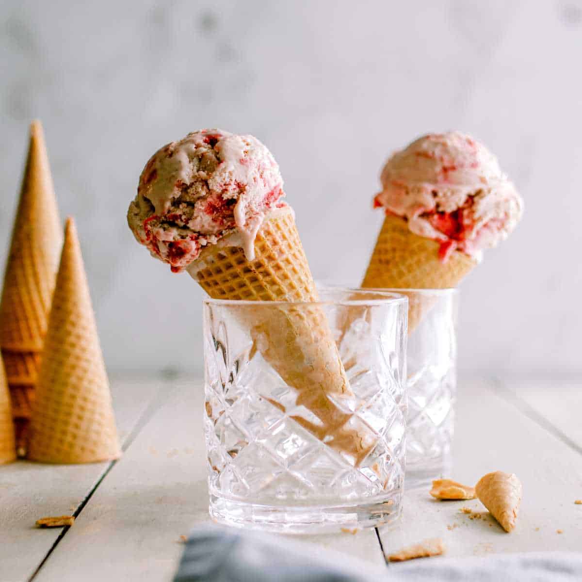 Two ice cream cones filled with strawberry ice cream.