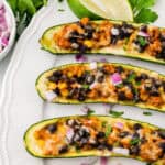 Three zucchini taco boats served on a white platter.