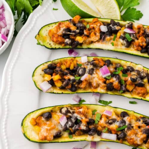 Three zucchini taco boats served on a white platter.