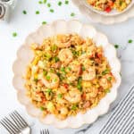 A plate of Cajun fried rice topped with shrimp and green onions.