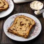 A slice of gluten free cinnamon raisin bread served on a white floral plate.
