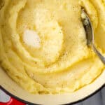 Gluten free mashed potatoes in a large pot topped with melted butter.