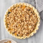 An unbaked pie topped with oatmeal crumble topping.
