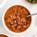 A bowl of chili sitting on a white table.