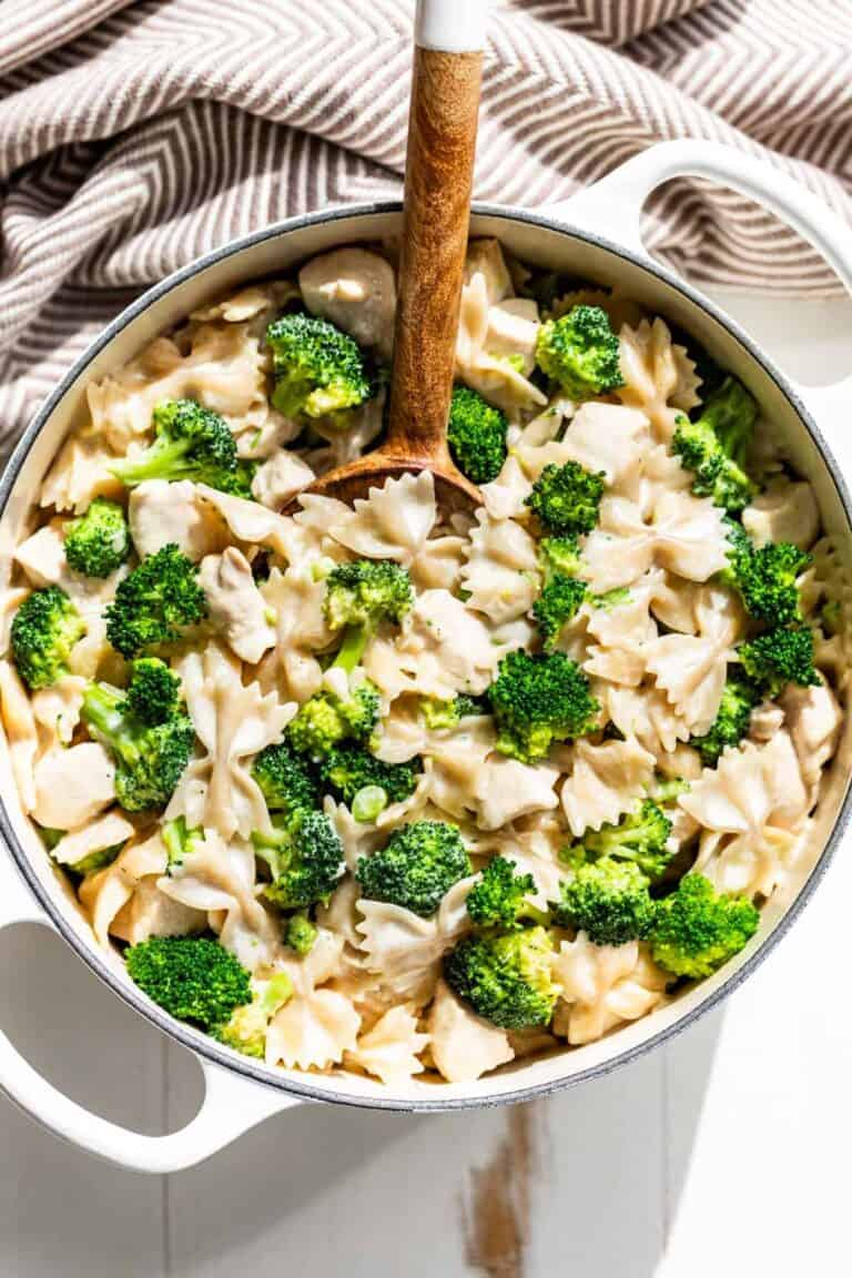 Broccoli and pasta in an alfredo sauce cooking in a dutch oven.