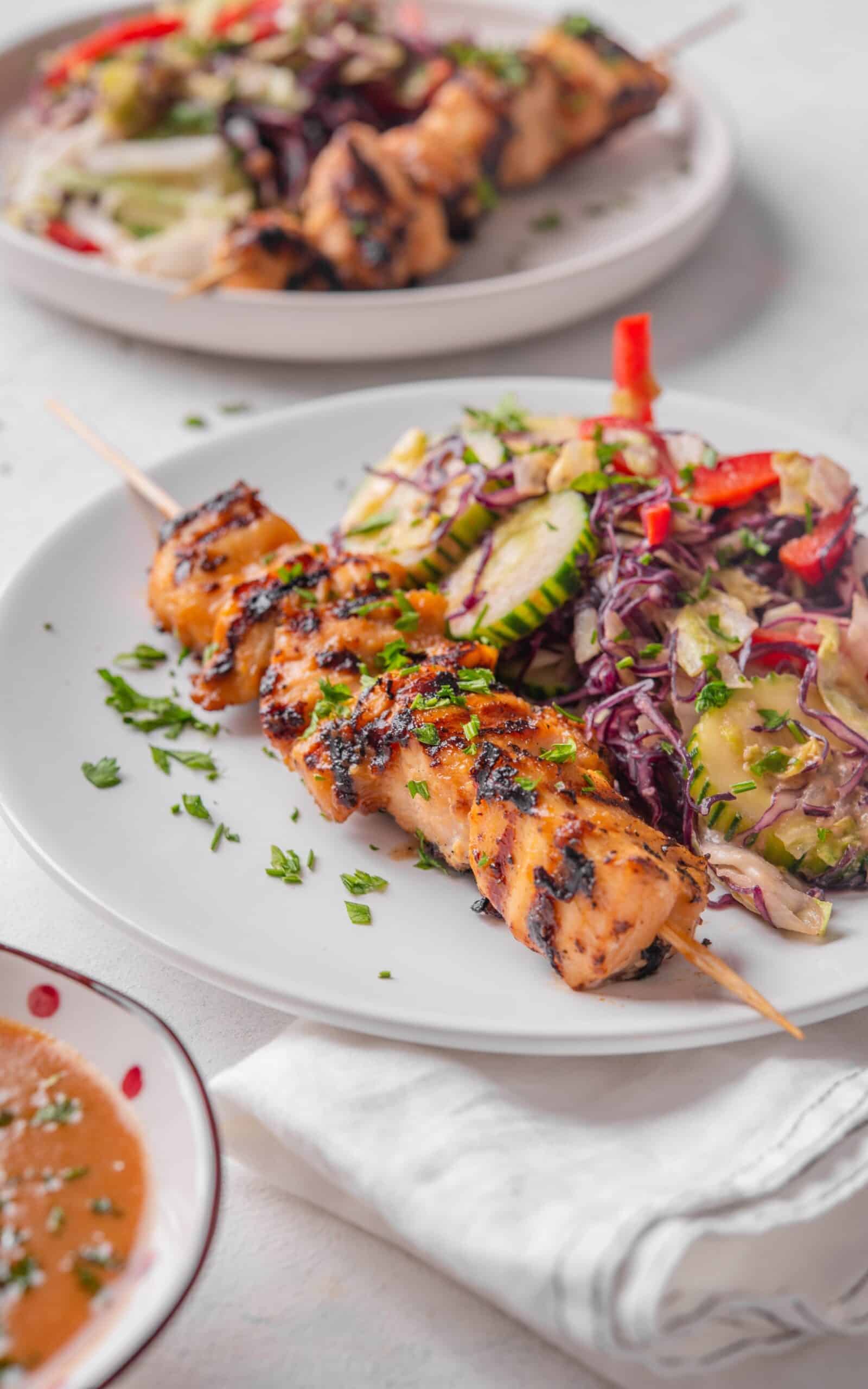 A plate of chicken satay with roasted vegetables.