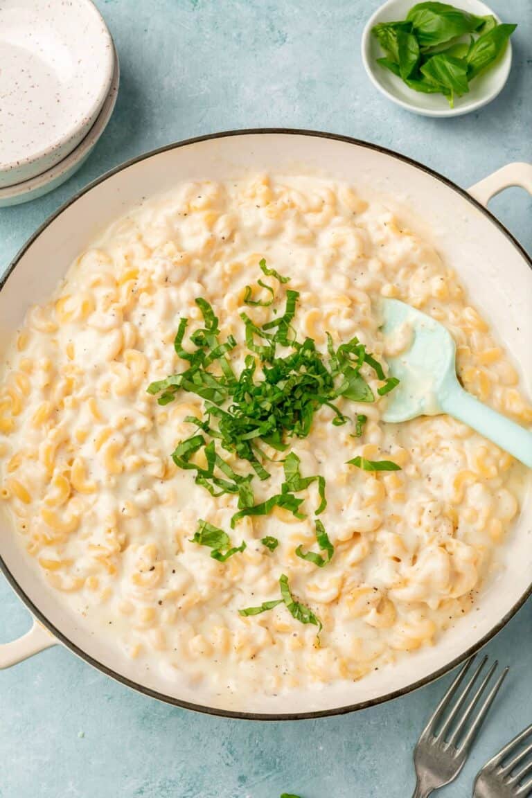 A dutch oven filled with macaroni and cheese and topped with parsley.